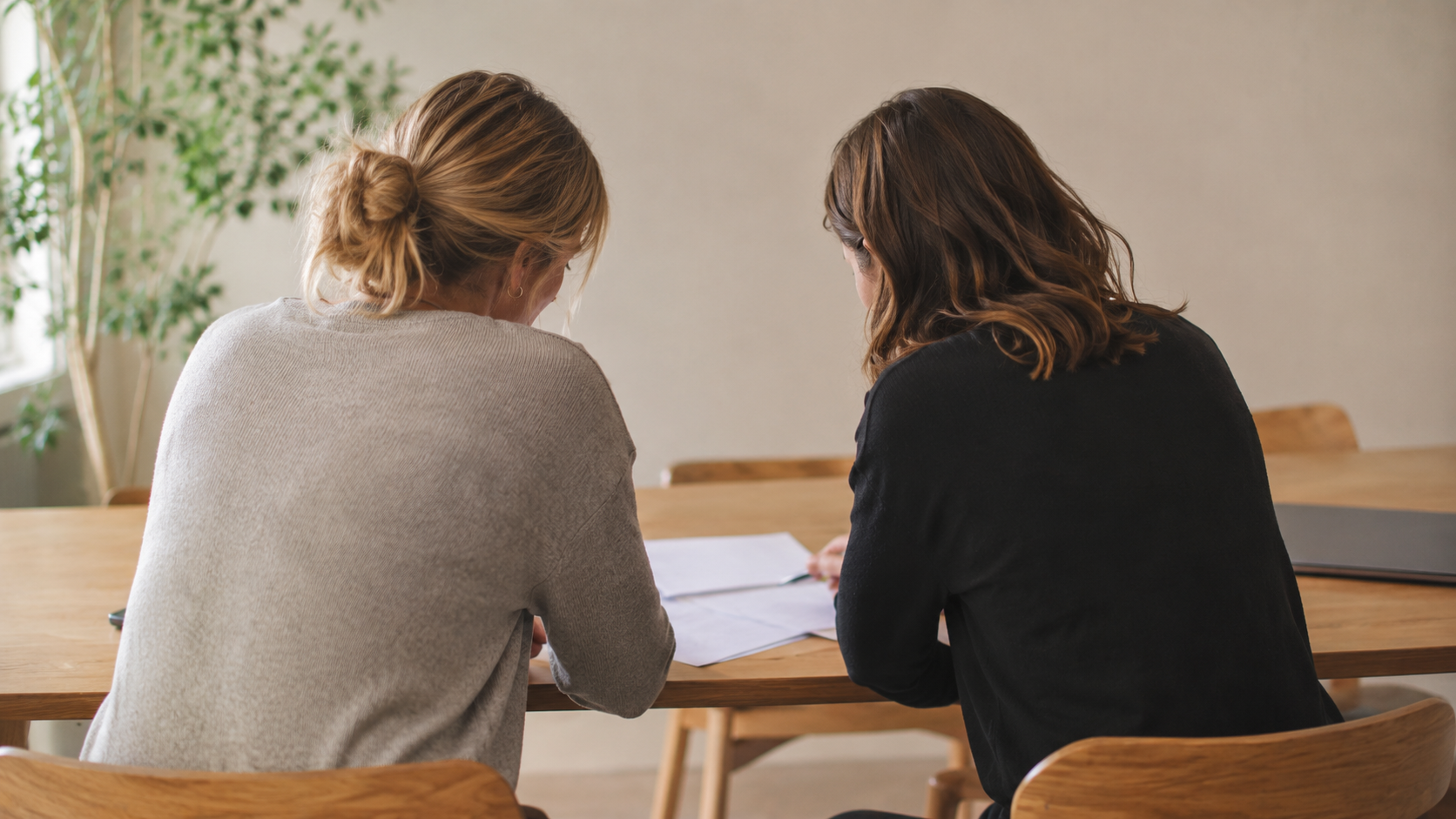 Twee vrouwen bekijken samen documenten aan tafel